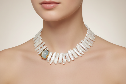 Pearl necklace with a central gemstone worn by a model on a neutral background