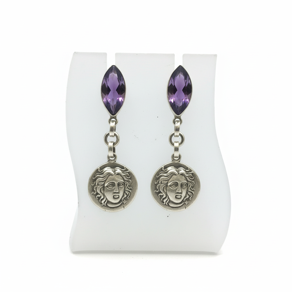 Pair of earrings with purple gemstones and face-like charms on a white display card.
