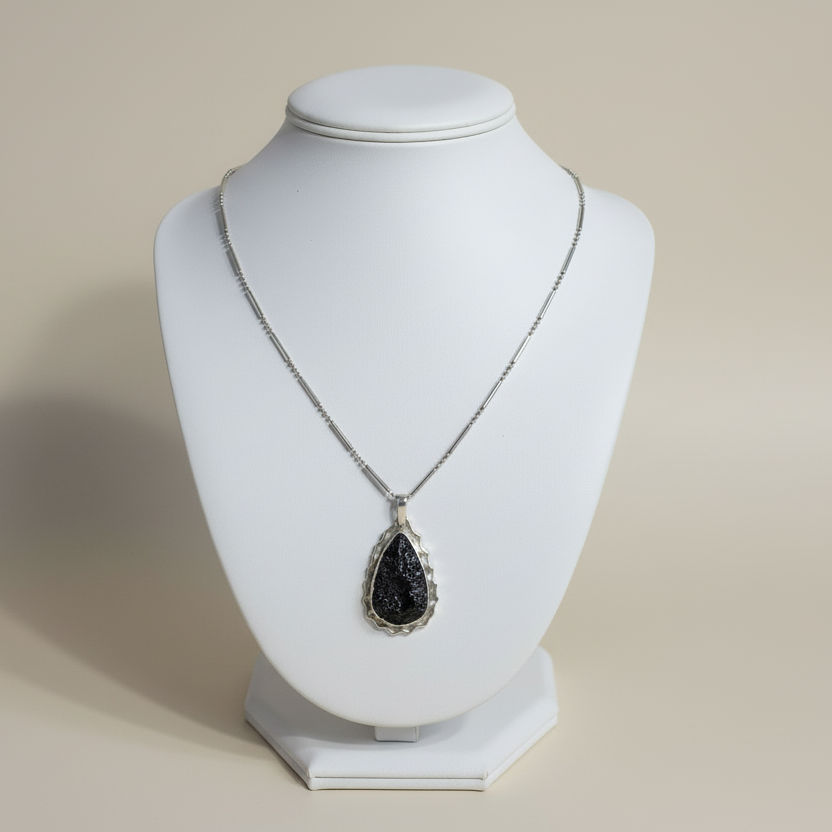 Necklace with a black pendant on a white mannequin bust against a beige background