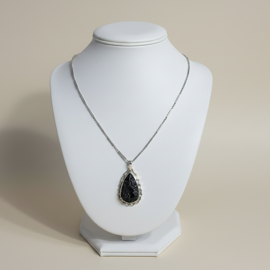 Necklace with a black pendant on a white mannequin bust against a beige background