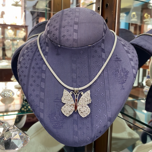 Butterfly necklace on a purple mannequin bust in a store setting