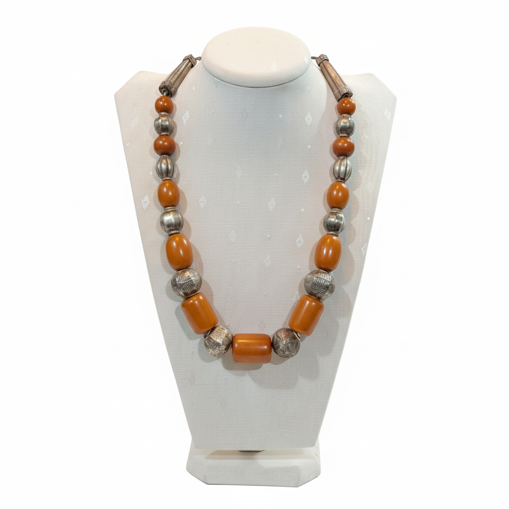 Necklace with orange and silver beads on a white stand
