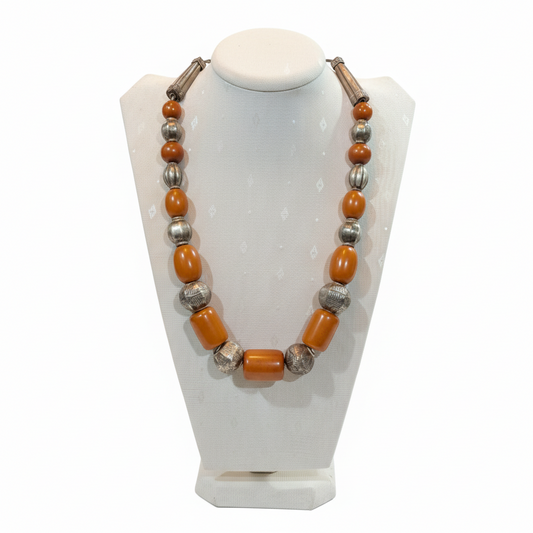 Necklace with orange and silver beads on a white stand