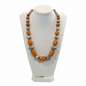 Necklace with orange and silver beads on a white stand