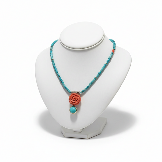 Necklace with turquoise beads and coral rose pendant on a white mannequin bust.