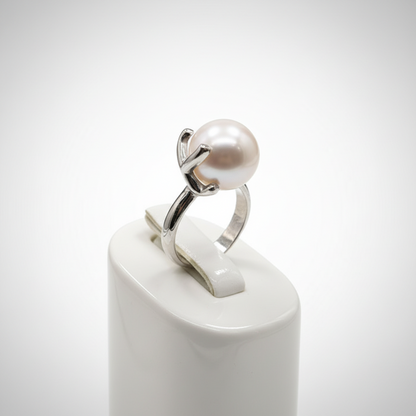 Silver ring with a pearl on a white pedestal against a light gray background