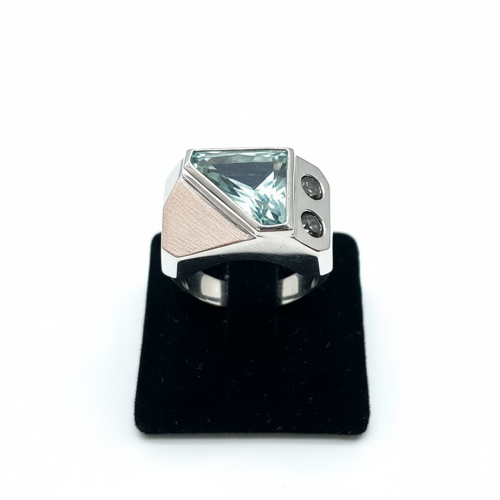 Silver ring with a large green gemstone on a black stand against a white background