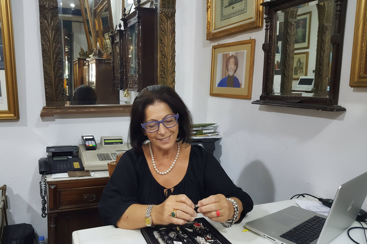 Woman organizing jewelry in a display case in a room with mirrors and decor.